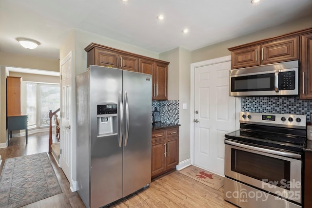 kitchen featuring light wood-style floors, stainless steel appliances, baseboards, recessed lighting, and decorative backsplash