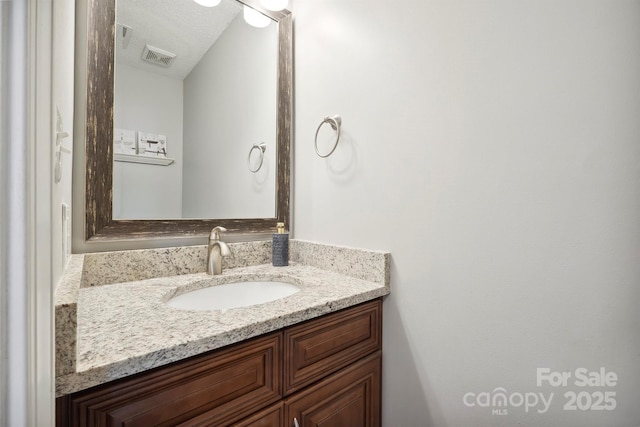 bathroom featuring visible vents, a textured ceiling, and vanity
