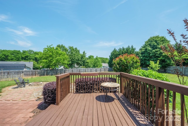 wooden terrace featuring a fenced backyard, a yard, an outdoor fire pit, and a patio area