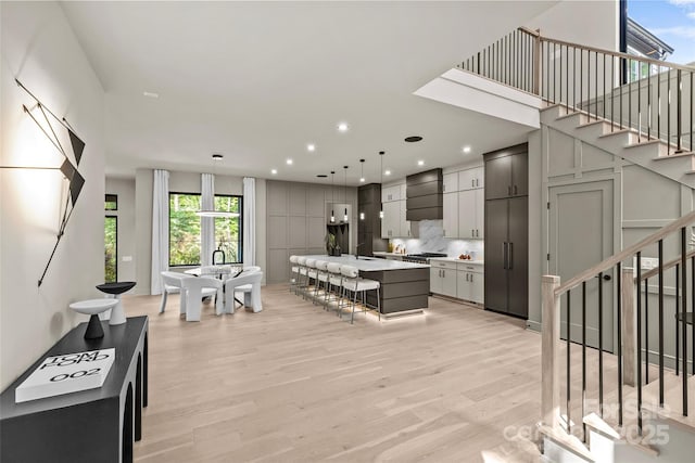 624 Heather Ln, Charlotte, NC 28209 - kitchen featuring light wood-style floors, a kitchen bar, light countertops, pendant lighting, and tasteful backsplash