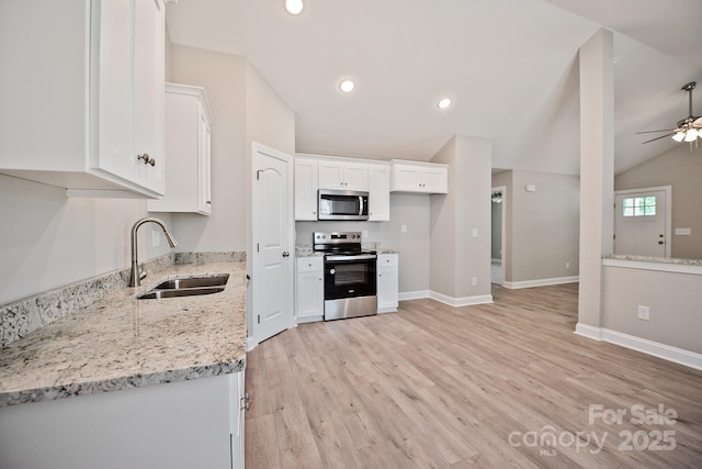 kitchen with a ceiling fan, a sink, lofted ceiling, stainless steel appliances, and white cabinetry