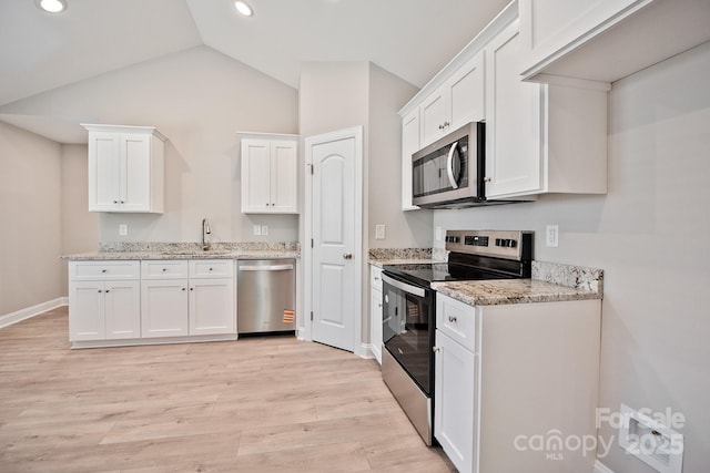 kitchen featuring white cabinets, light stone counters, light wood-style flooring, vaulted ceiling, and stainless steel appliances