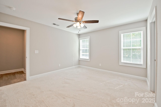 unfurnished bedroom with light colored carpet, baseboards, visible vents, and multiple windows