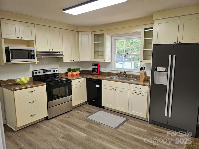 1109 Reid Harkey Rd, Matthews, NC 28105 - kitchen with black appliances, a sink, under cabinet range hood, dark countertops, and glass insert cabinets