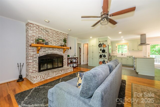 13030 Mayes Rd, Huntersville, NC 28078 - living area featuring a brick fireplace, wood finished floors, a ceiling fan, and ornamental molding