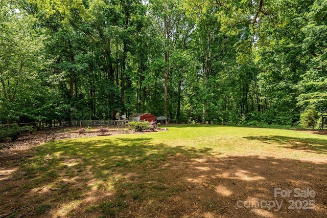 13030 Mayes Rd, Huntersville, NC 28078 - view of yard featuring a wooded view, a storage shed, fence, and an outdoor structure