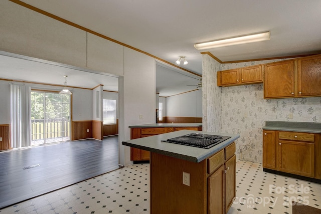 kitchen featuring crown molding, light floors, black electric stovetop, and brown cabinets