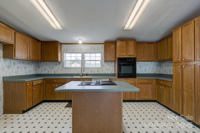 kitchen featuring a sink, light floors, brown cabinetry, and black appliances
