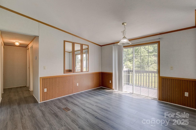 unfurnished room with crown molding, wood finished floors, and a wainscoted wall