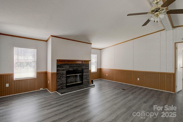 unfurnished living room with ceiling fan, wainscoting, wood finished floors, and a fireplace
