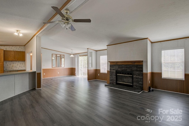 unfurnished living room with ornamental molding, ceiling fan, and a wainscoted wall
