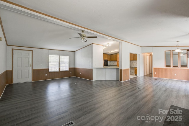 unfurnished living room featuring ornamental molding, wainscoting, ceiling fan, and dark wood finished floors