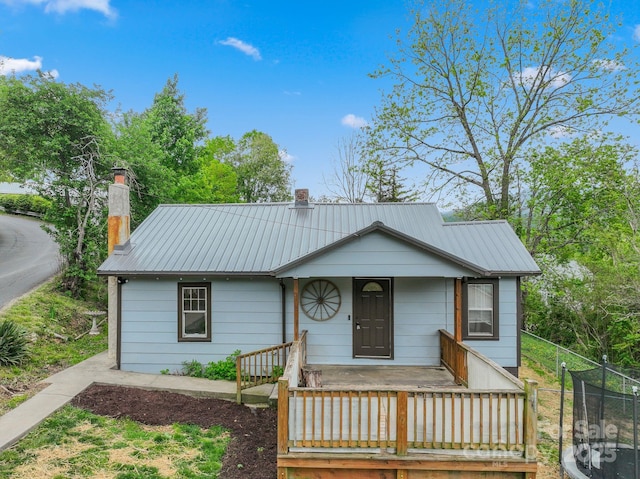 view of front of property featuring a chimney, metal roof, and fence