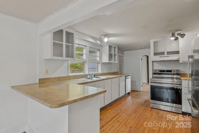kitchen featuring stainless steel electric range, under cabinet range hood, a sink, dishwasher, and a peninsula