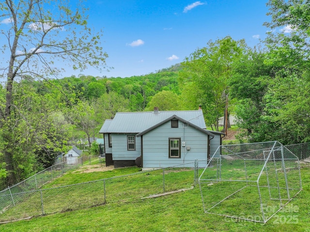 rear view of property featuring a chimney and a view of trees