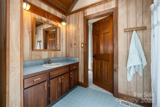 bathroom with wooden walls, vanity, visible vents, and lofted ceiling