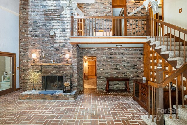 1160 Walton Pl, Salisbury, NC 28146 - unfurnished living room with brick flooring, a brick fireplace, stairway, a ceiling fan, and a high ceiling