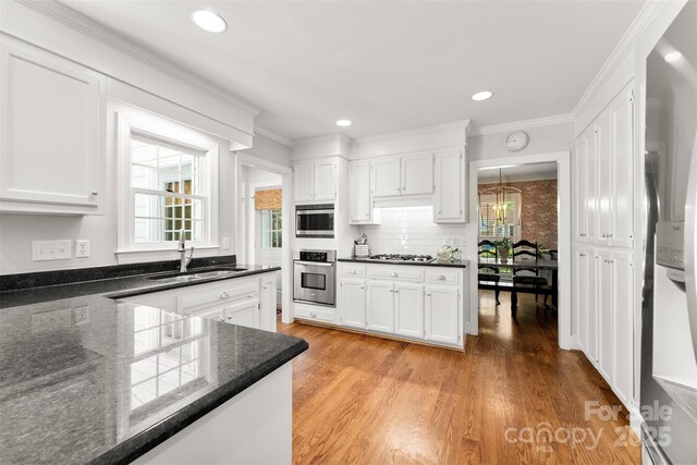 kitchen with white cabinets, stainless steel appliances, a sink, and light wood-type flooring