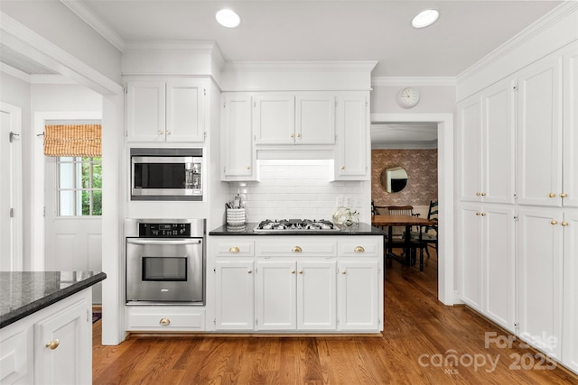 kitchen with tasteful backsplash, wood finished floors, white cabinets, and stainless steel appliances