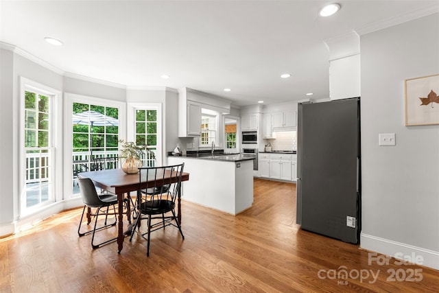 dining room with crown molding, recessed lighting, and light wood-type flooring