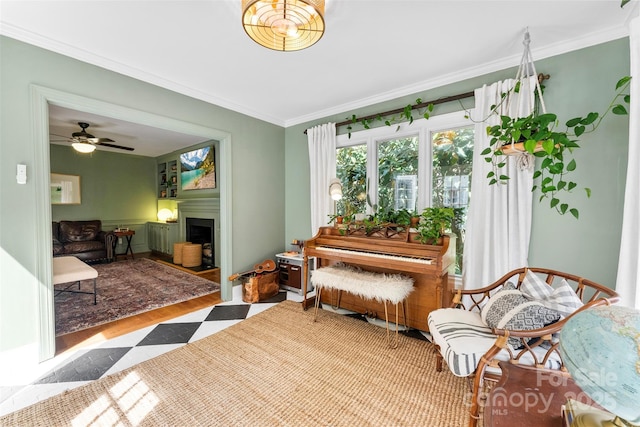 living area with crown molding, wood finished floors, and a fireplace
