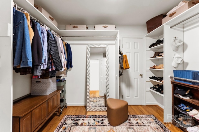 walk in closet with light wood finished floors