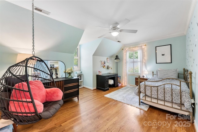 bedroom with visible vents, crown molding, wood finished floors, baseboards, and vaulted ceiling