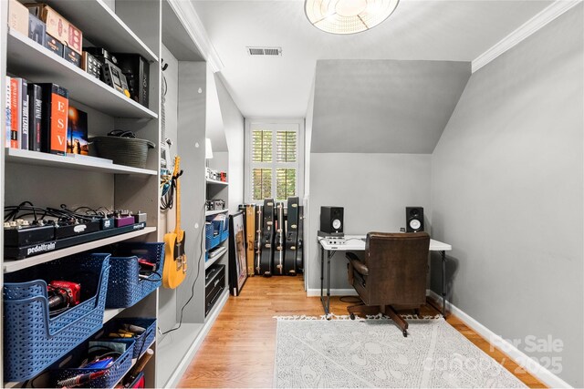 office with baseboards, wood finished floors, vaulted ceiling, visible vents, and ornamental molding