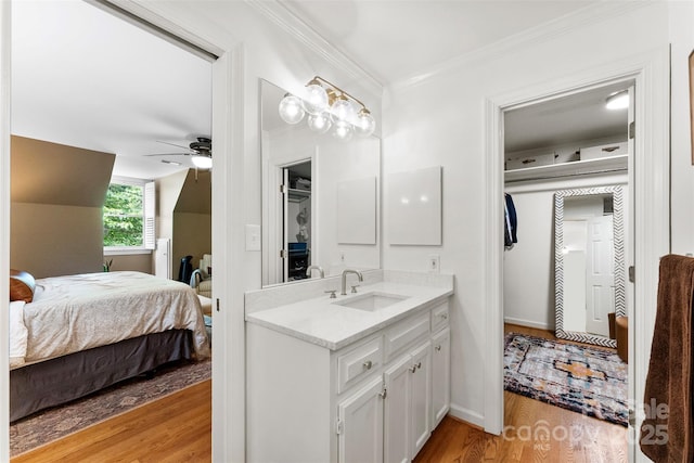 bathroom with vanity, ornamental molding, wood finished floors, ceiling fan, and ensuite bath