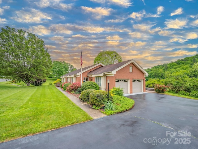 view of home's exterior with a lawn, asphalt driveway, a chimney, and a garage