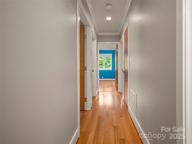 corridor featuring light wood finished floors, crown molding, and baseboards