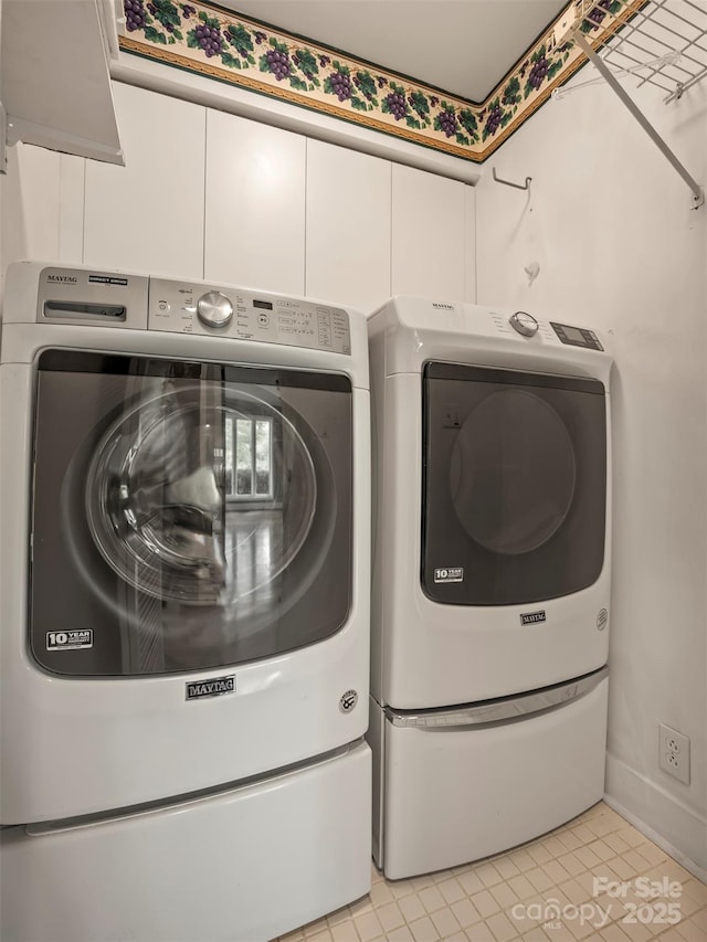 laundry area featuring separate washer and dryer, light tile patterned floors, and baseboards