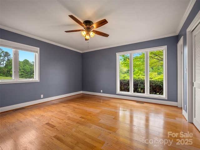 empty room with a ceiling fan, light wood-type flooring, crown molding, and baseboards