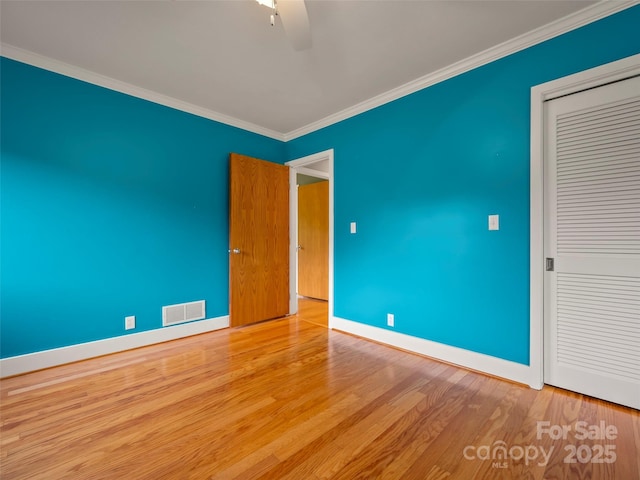 unfurnished bedroom with crown molding, baseboards, wood finished floors, a closet, and ceiling fan
