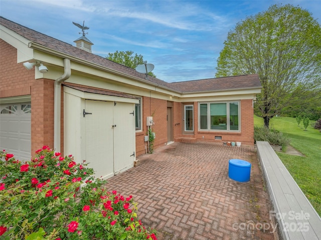 view of front of house with brick siding, a garage, a front yard, and a patio area