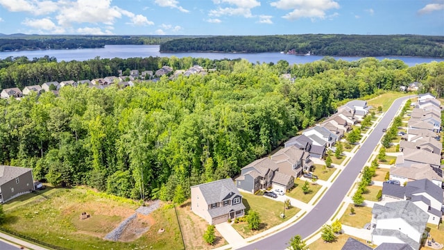 aerial view of residential area featuring a forest and a nearby body of water