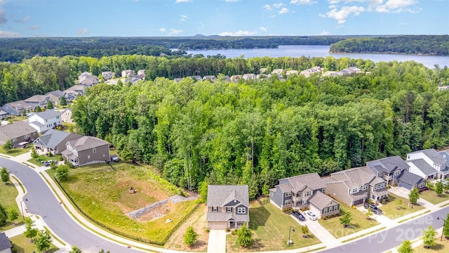 aerial view of residential area featuring a heavily wooded area and a large body of water