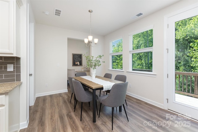 dining room featuring wood finished floors, a chandelier, and baseboards