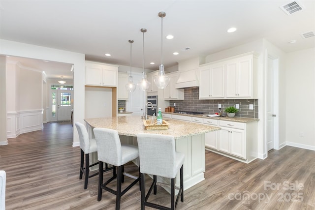 kitchen with stainless steel gas cooktop, white cabinetry, light wood-style floors, tasteful backsplash, and recessed lighting