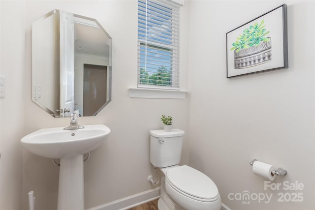 half bathroom featuring toilet, baseboards, ornamental molding, and wood finished floors