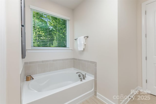 full bath with a garden tub and baseboards