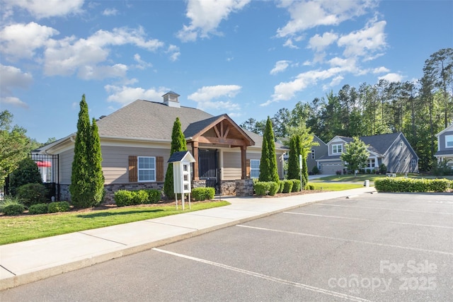 view of front of home with stone siding, uncovered parking, and a front lawn