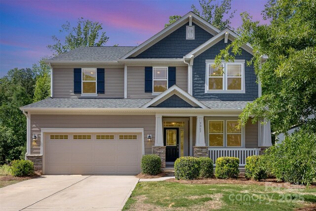 craftsman-style house with a garage, a porch, driveway, and roof with shingles