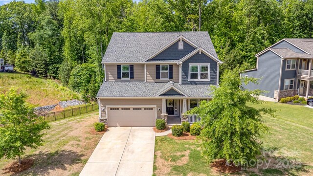 craftsman-style house with an attached garage, concrete driveway, and a porch