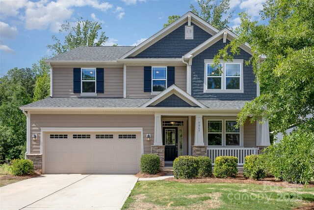 craftsman house with an attached garage, covered porch, concrete driveway, and roof with shingles