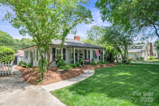 view of front facade featuring a front lawn, a porch, and a chimney