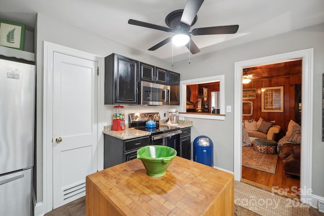 kitchen with dark cabinets, wood finished floors, baseboards, ceiling fan, and appliances with stainless steel finishes