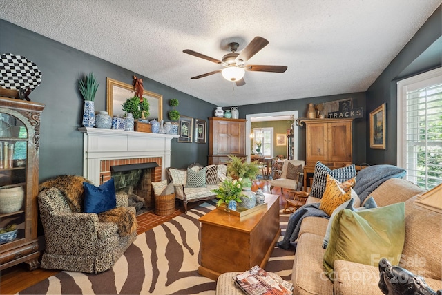 living room featuring a fireplace, a textured ceiling, and a ceiling fan