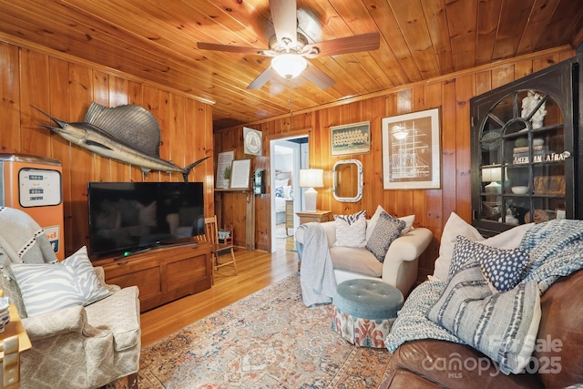 living area with wood walls, ceiling fan, wooden ceiling, and wood finished floors