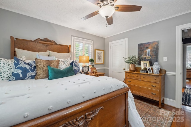 bedroom with wood finished floors, a textured ceiling, crown molding, a ceiling fan, and baseboards
